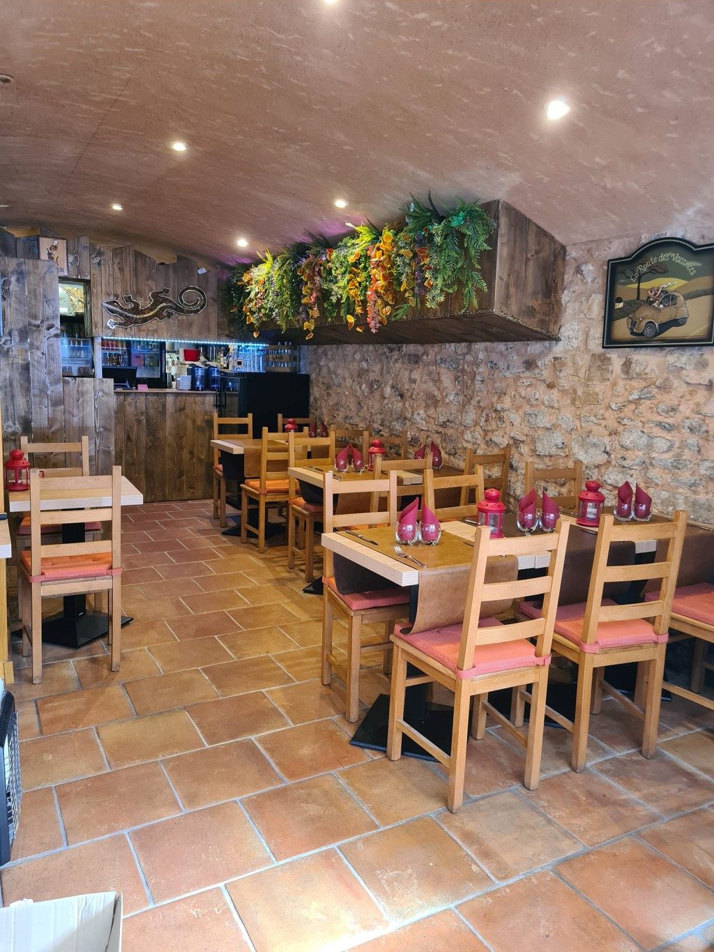 La salle voûtée en pierre apparente, tables en bois dressées et plantes suspendues